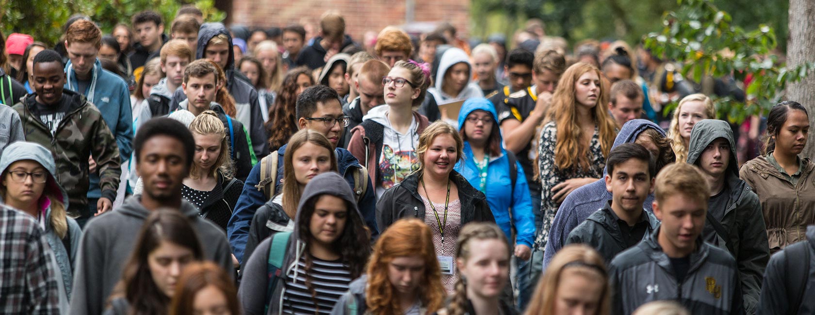 A crowd of dozens of PLU students walk through upper campus during Convocation 2016.