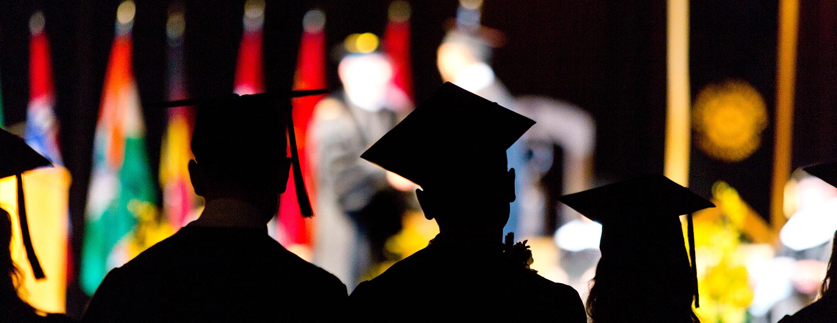 Dressed in graduation gap and gowns, students look up at the stage at PLU's 2016 commencement ceremony.