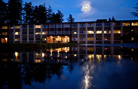 Foss Hall and its reflection in a pond from the moonlight.