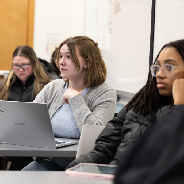 students studying in classroom, one in black another in grey and another in black