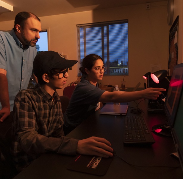 Students working on computers and getting help from their professor