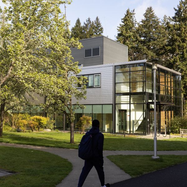 Student walking outside of Morken on a sunny day while wearing hoodie