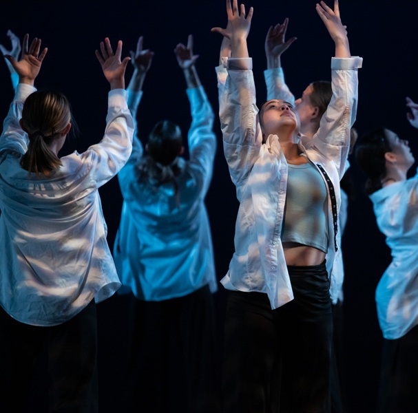 Students in white shirts with hands up