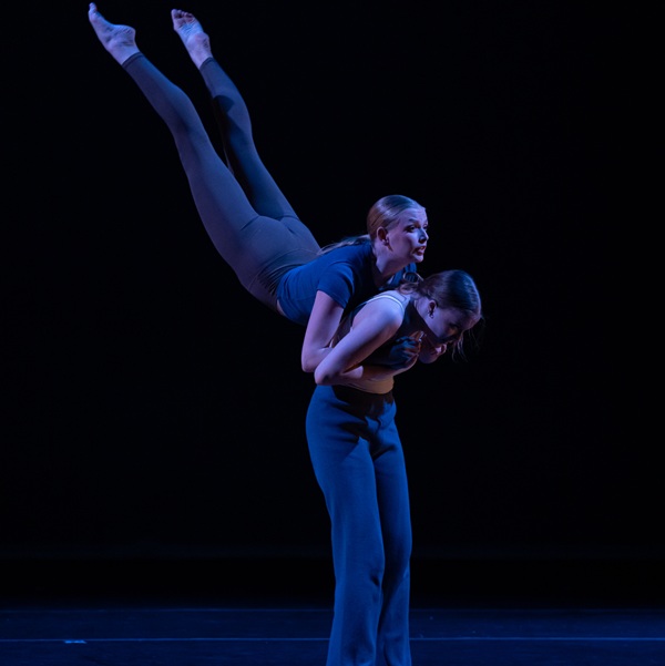 Two dance performers holding each other as they are completing a shape