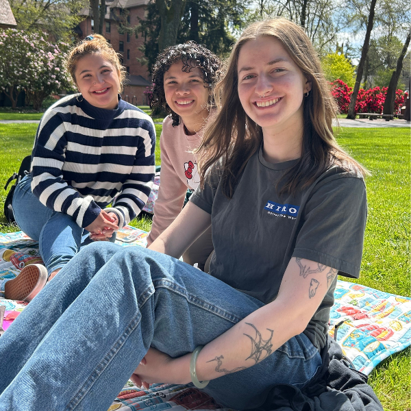 students smiling on picnic mat at redsquare