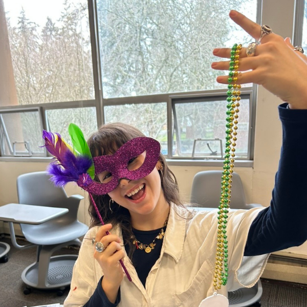 student wearing mask in morken while holding plastic necklace