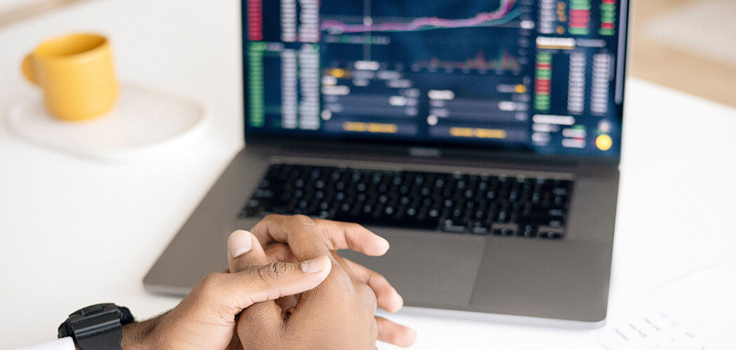 A person crossing his hands in front of a computer with data on it