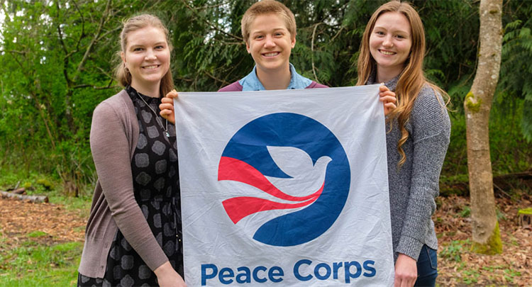 PLU almni holding a Peace Corps flag.