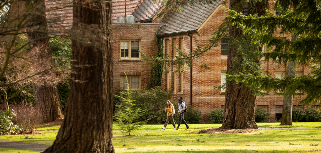 Two students walking on campus pathway in front of Xavier Hall.