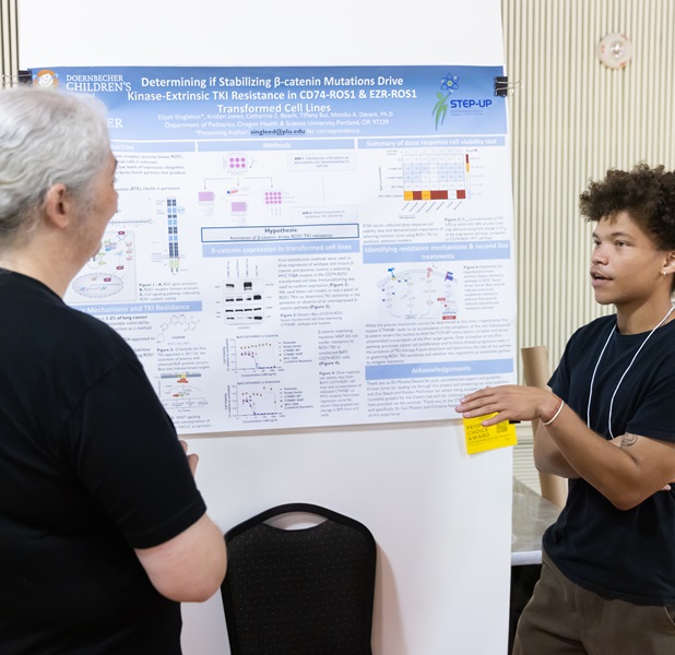 A student and a professor having a conversation in front of a poster