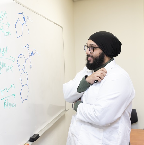 Student solving an equation at the board