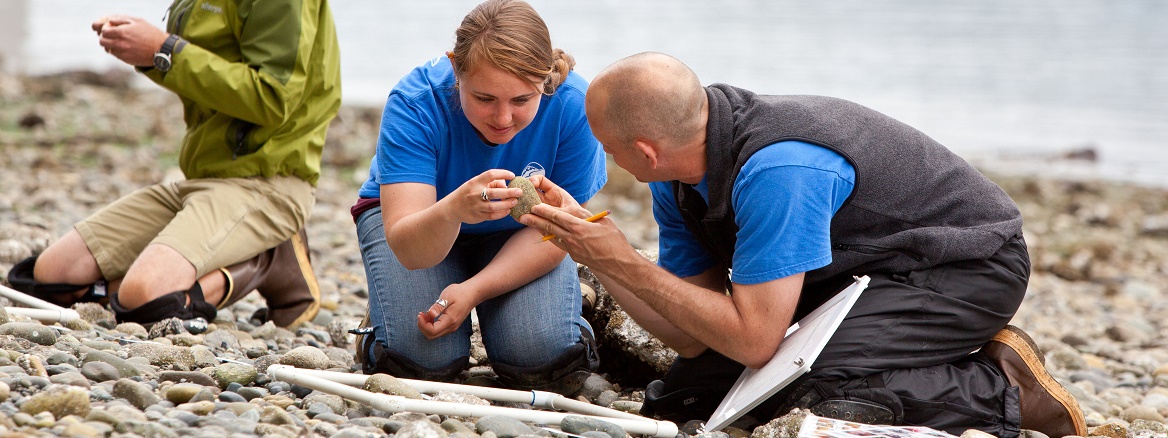 Professor and student on the beach looking at marine biology