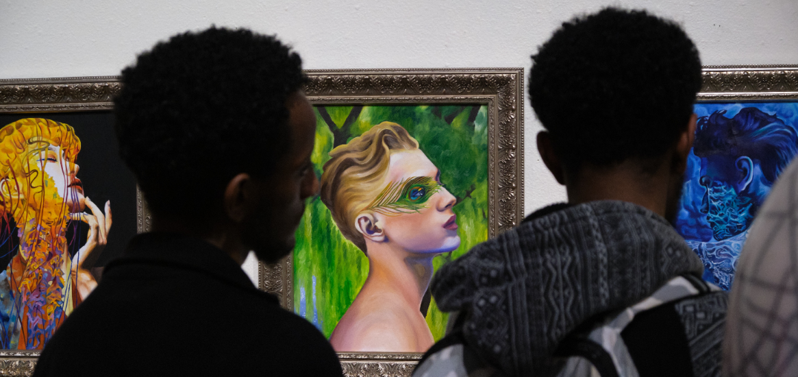 Two students viewing an artistic side profile portrait from the Juried Student Art Exhibit 2022