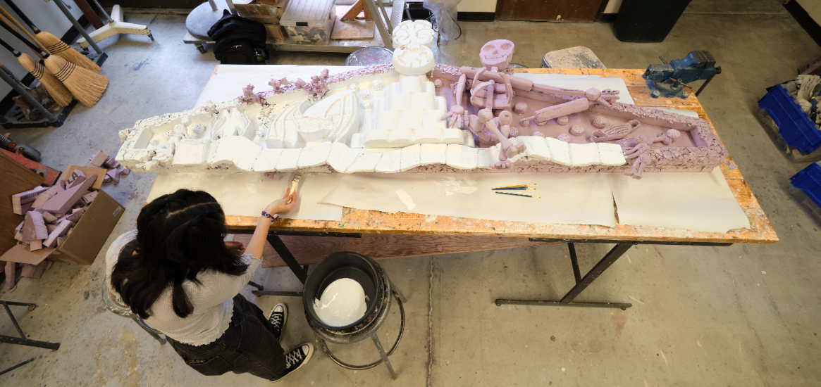 An overhead view of student working on a large scale ceramics piece in the ceramics studio located in Ingram Hall