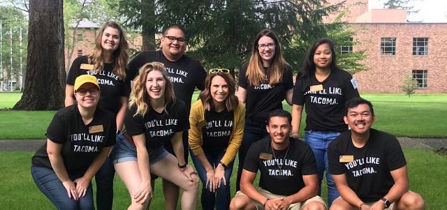 PLU Admission Counselors pose for a group photo, all wear t-shirts that read You'll Like Tacoma