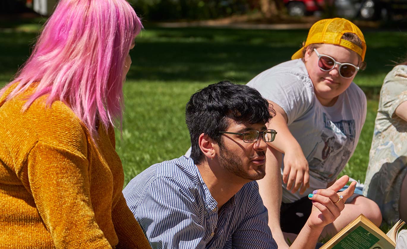 PLU students sitting outside in the sunshine on campus