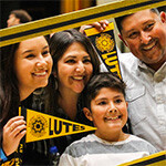 Family of PLU student holding pennants and smiling