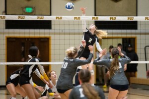 A PLU volleyball player mid-leap to spike a ball during a match