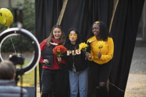 Three students posing with flowers in Red Square during Bjug Day Celebration.