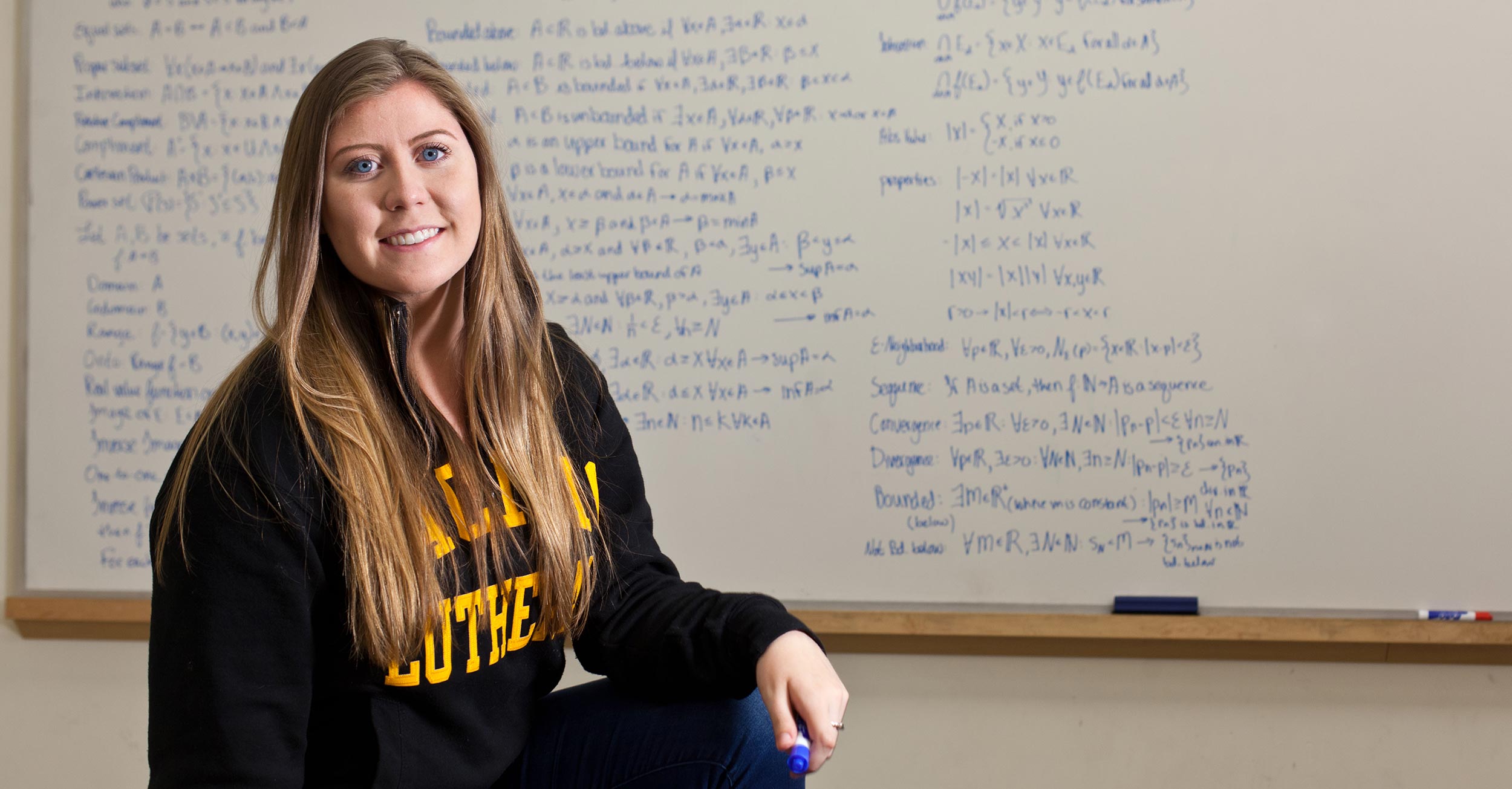 PLU-student-Chaney-Skadsen-poses-for-a-photo-in-front-of-a-chalkboard