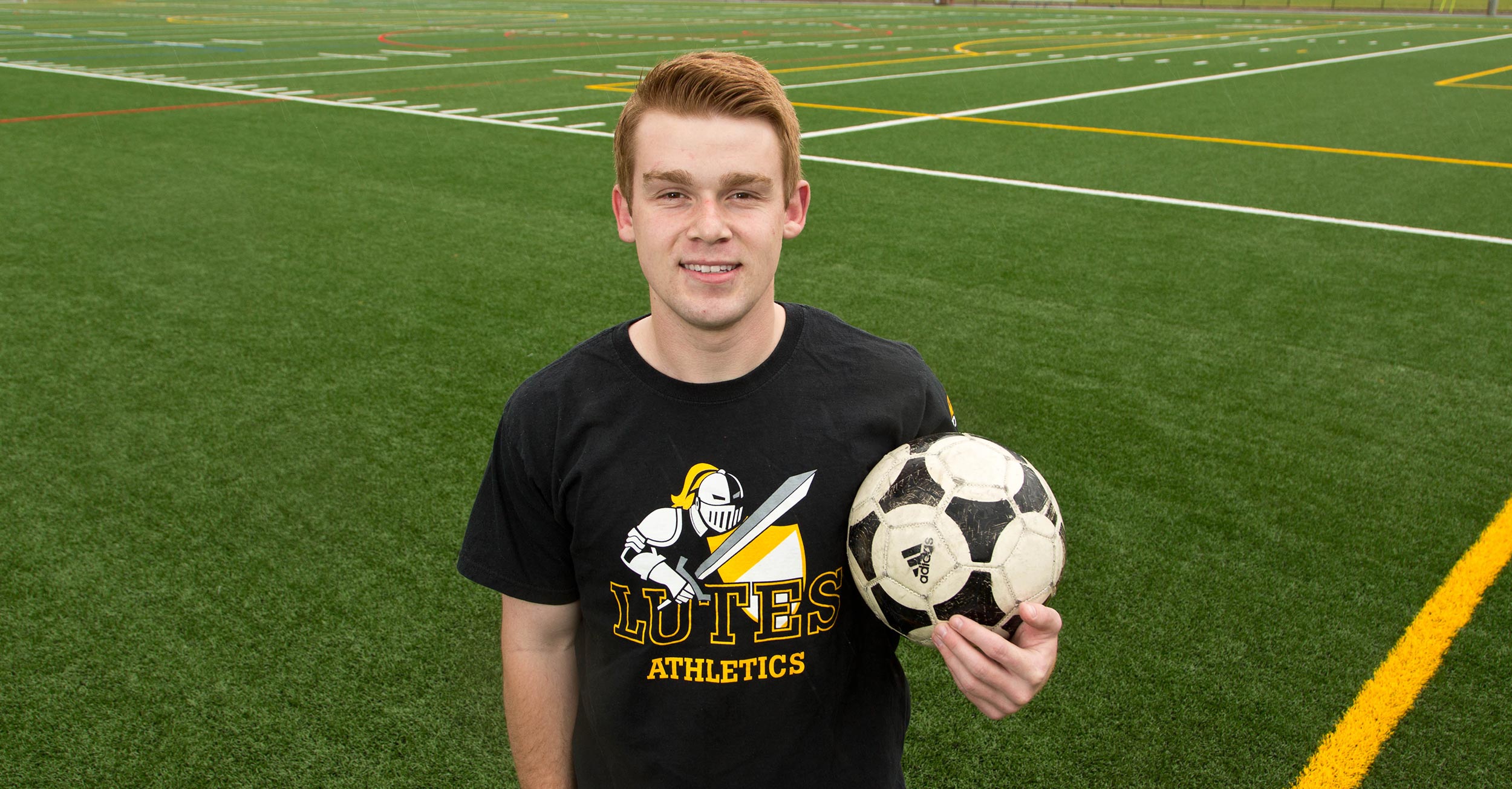 PLU-student-Todd-Hoagland-holding-a-soccer-ball-and-standing-on-the-PLU-soccer-field