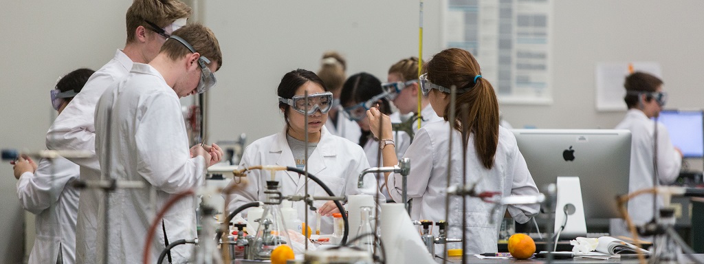 Students in goggles and white lab coats work in the PLU chemistry lab