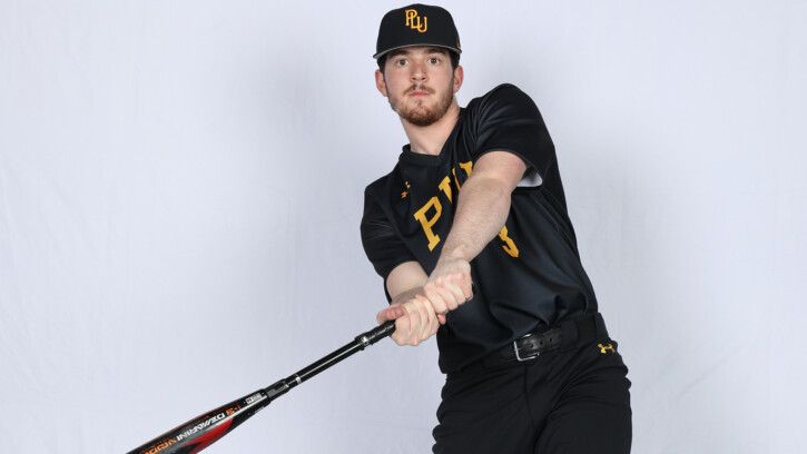 Connor Lemma is wearing a black PLU baseball uniform. He is shown swinging a bat inside a white studio.