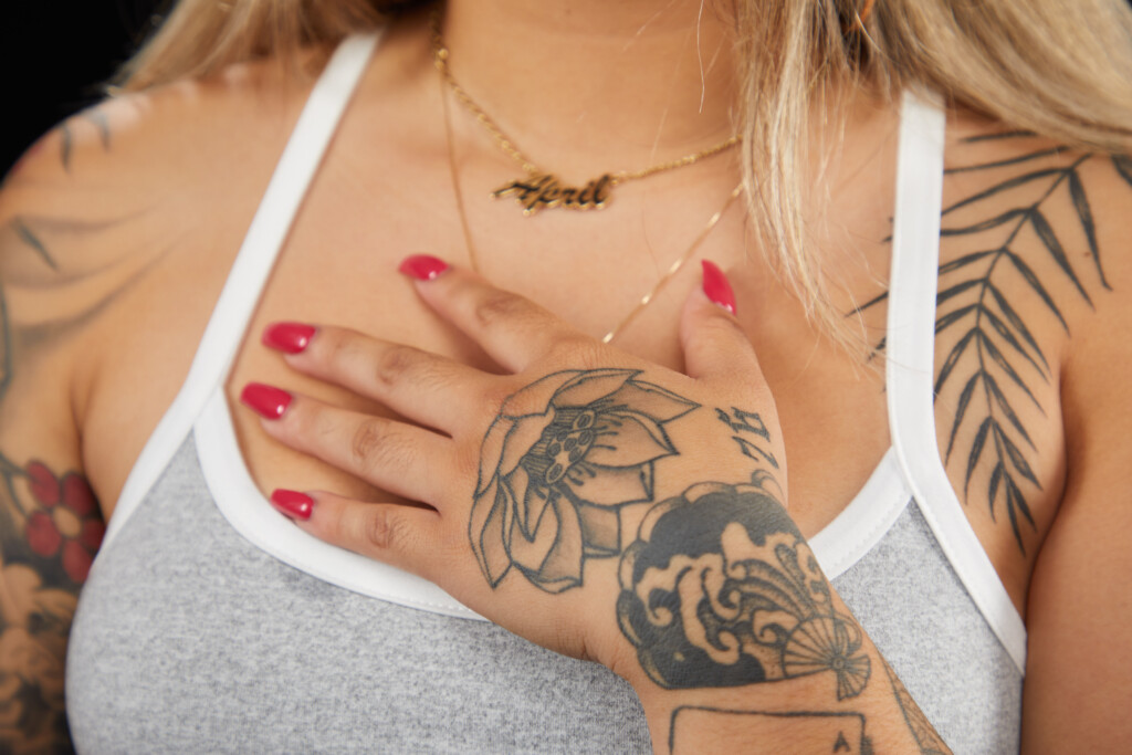 April Reyes hand can be shown resting on her chest. She has a lotus tattoos on the front of her hand.
