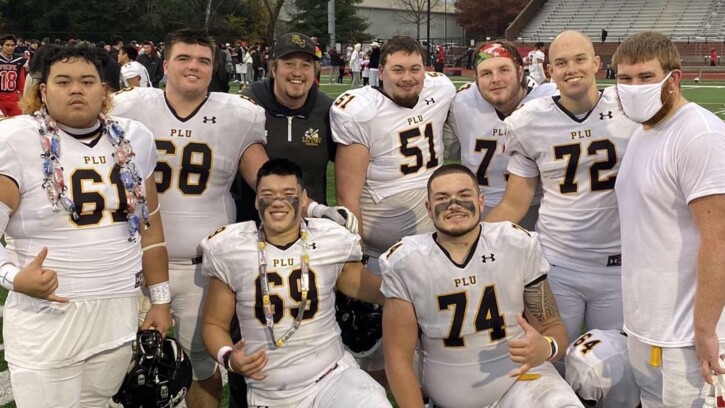 Zach willis is center in a black jacket surrounded by 8 male football players.