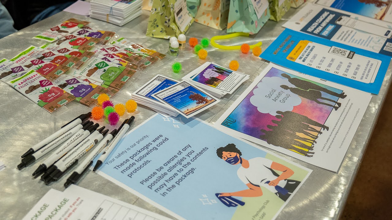 Mental Health flyers sit on a table alongside pens, fidget toys and snacks.