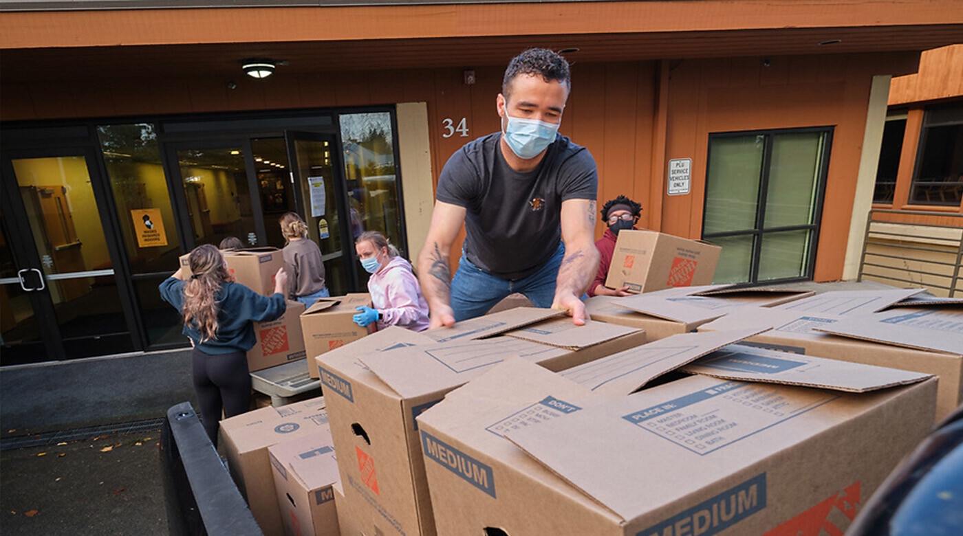 Justin Freeyman loads boxes of Thanksgiving meals onto a truck while wearing a mask.