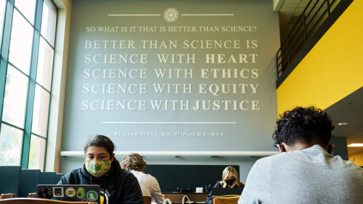 Four PLU students sit spread out at two tables in the Rieke Science building.