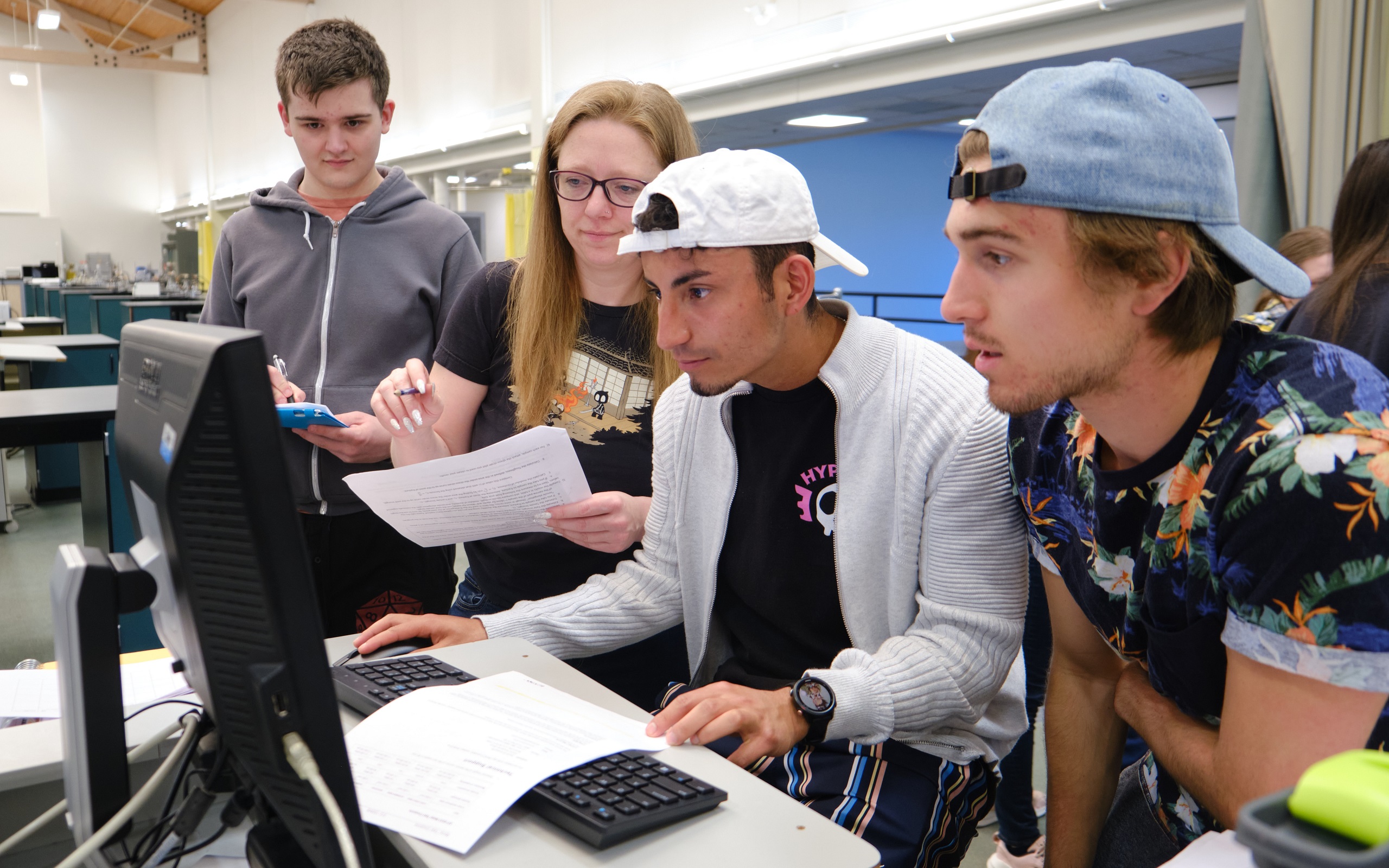 Students gathered around a computer work on stress testing different materials in a physics lab class