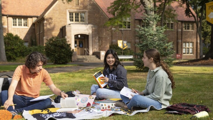 Students study on the grass outside Xavier building on a sunny day on campus