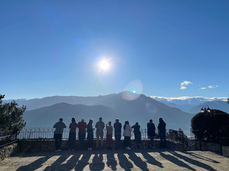 Students are silhouetted and are looking at a large mountain in Greece.