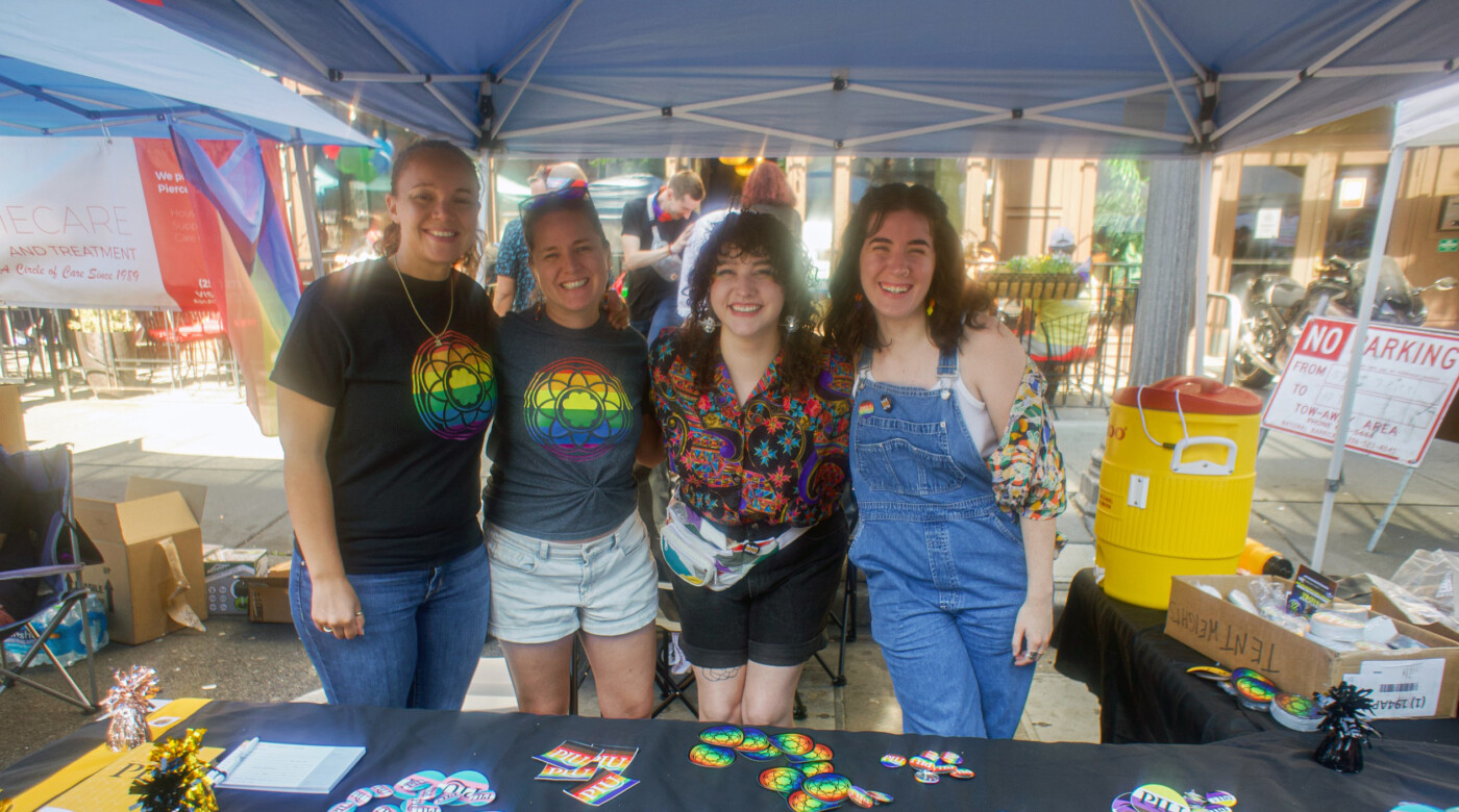 Four people smile into the camera wearing pride gear at Tacoma Pride 2023.