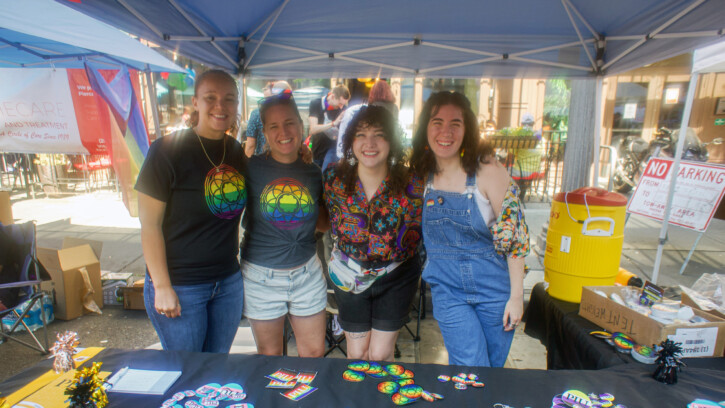 Four people smile into the camera wearing pride gear at Tacoma Pride 2023.