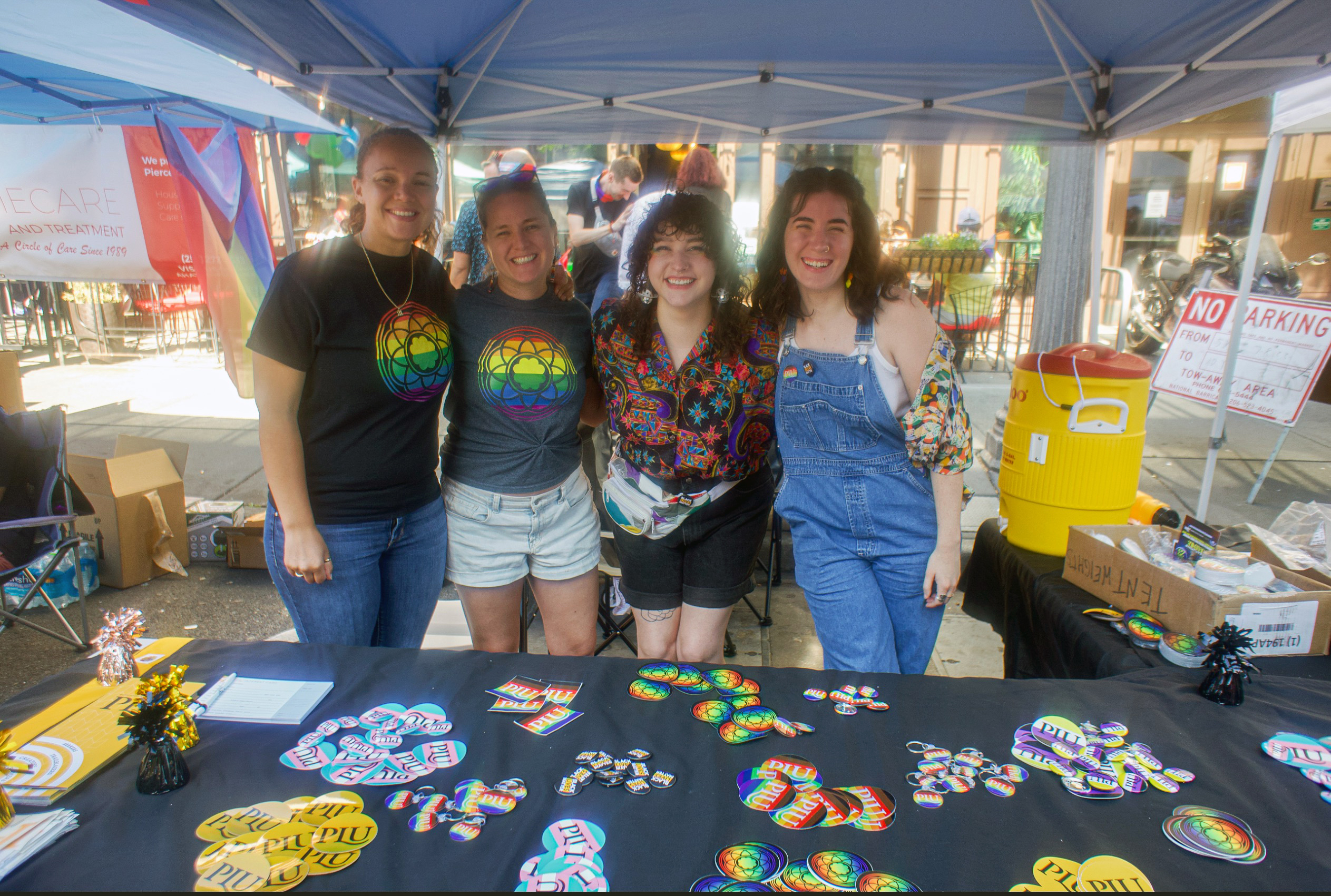 Four people smile into the camera wearing pride gear at Tacoma Pride 2023.