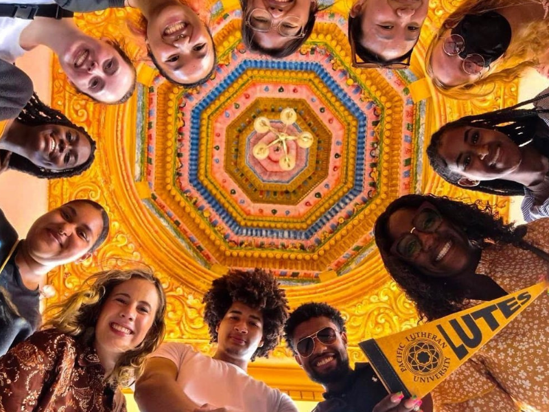 Trinidad & Tobago Students look down into the camera they are standing in a circle and there is a ornate golden ceiling above them.