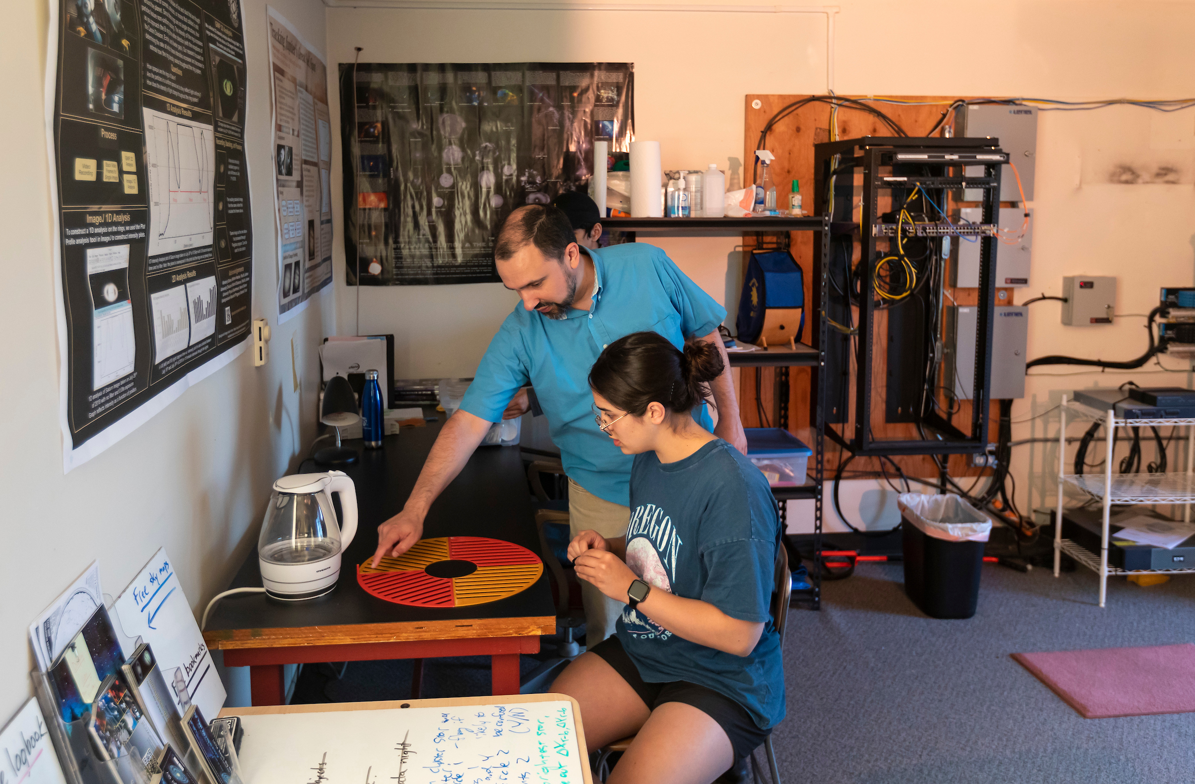 A professor works with a student on a mask for a telescope.