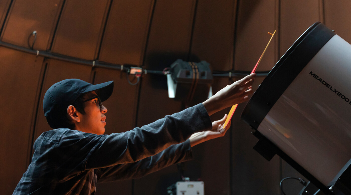 A student puts a orange mask over a telescope.