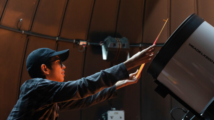 A student puts a orange mask over a telescope.