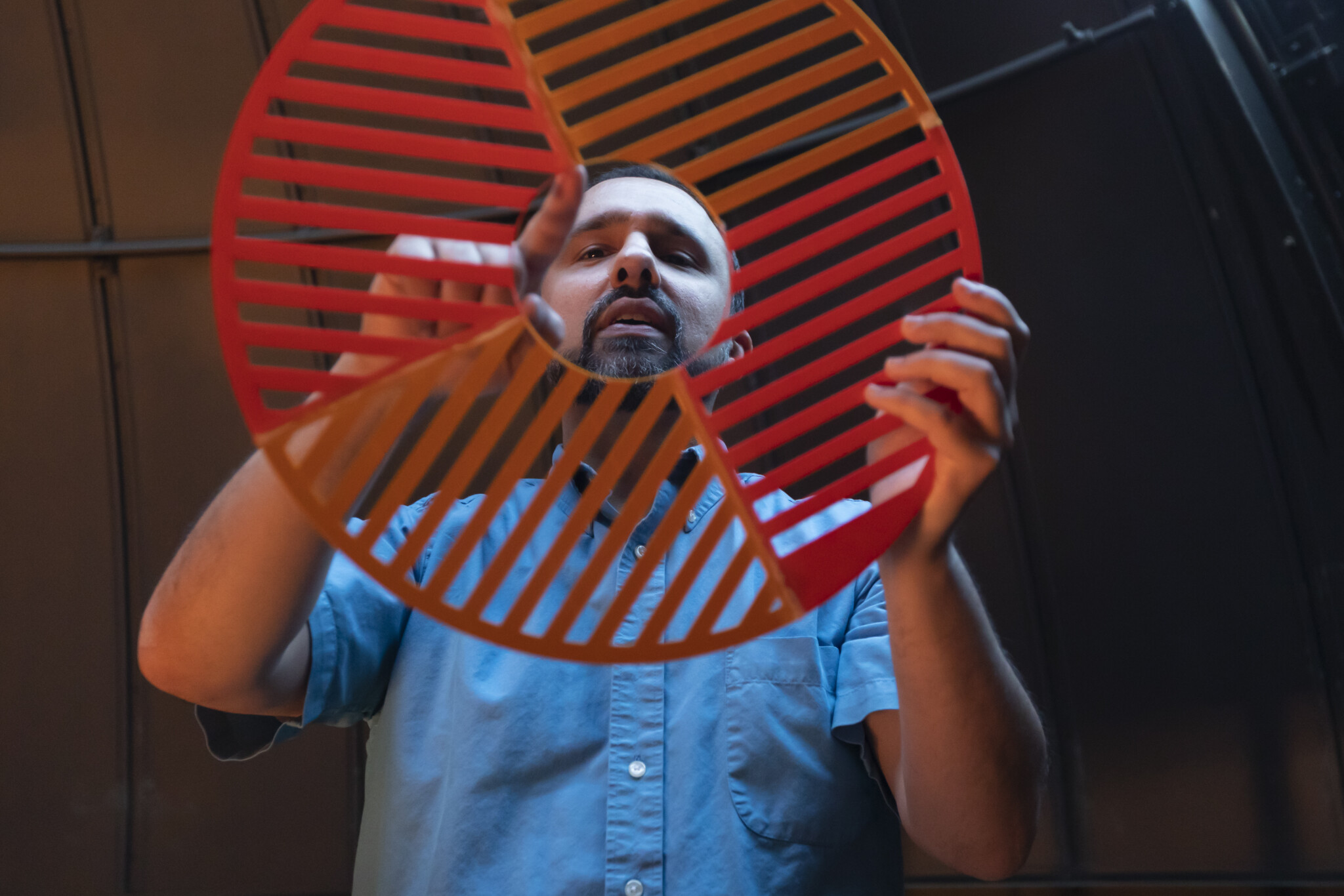 A professor looks at a red mask that will be used to put over a telescope.