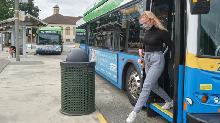PLU student, Kenzie Knapp, steps off a Pierce County transit bus at the transit center just a couple blocks away from the PLU campus. In the background is another bus.