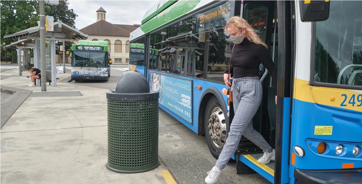 PLU student, Kenzie Knapp, steps off a Pierce County transit bus at the transit center just a couple blocks away from the PLU campus. In the background is another bus.