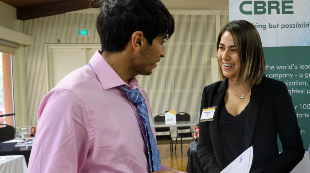 career Student meets with employer at PLU career fair. The two people are facing each other and are in mid conversation.