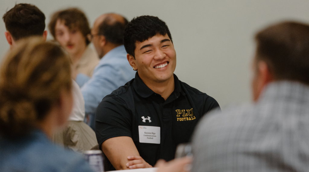 A PLU student is sitting at a table at a networking event.