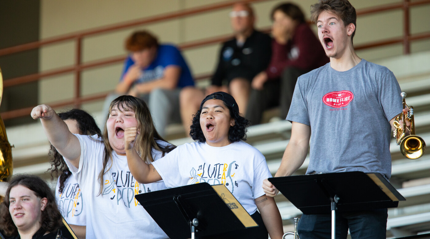 Students in the band cheer on the football team from the stand.