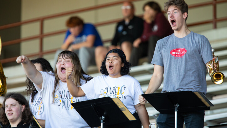 Students in the band cheer on the football team from the stand.