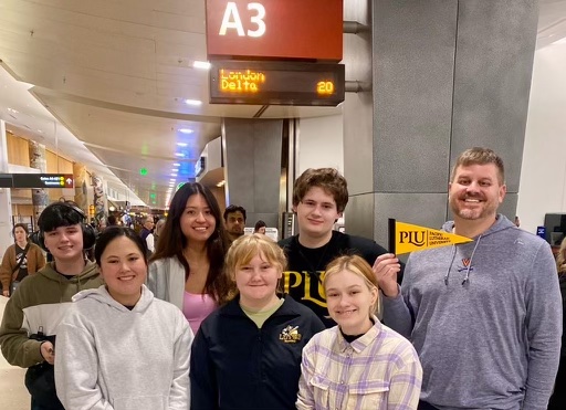 Student stand together at the airport and look into the camera and smile.